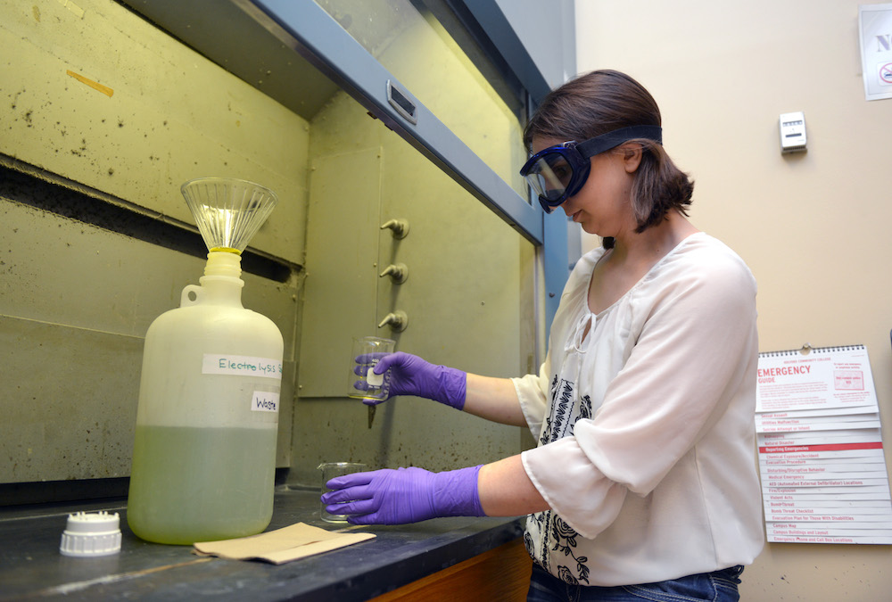 A chemistry student works with liquids under a fume hood